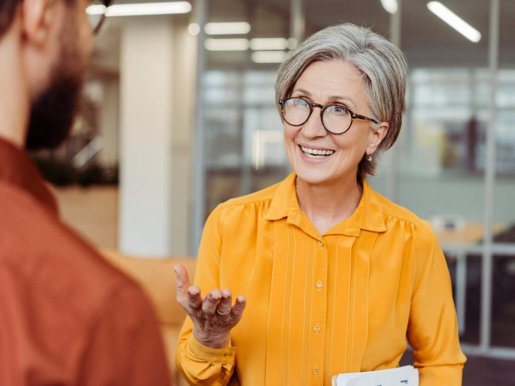 a light-skinned woman in a yellow blouse reviews the responsibilities of a real estate agent with her client