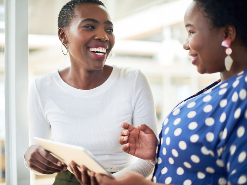 a dark-skinned female real estate agent with cropped pixie hair cut working to help a first-time homebuyer with dark skin in a blue polka dot blouse find her dream home