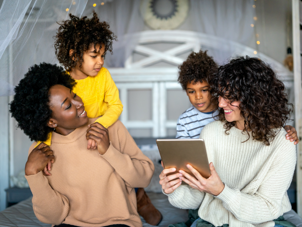 a young same-sex female presenting couple sits with their two children reviewing the mortgage financial readiness steps they should take to buy their first home